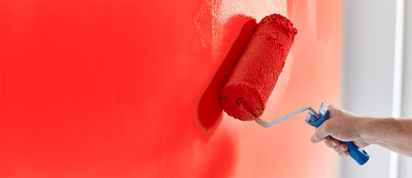 Close-up of a wide paint roller loaded with red paint